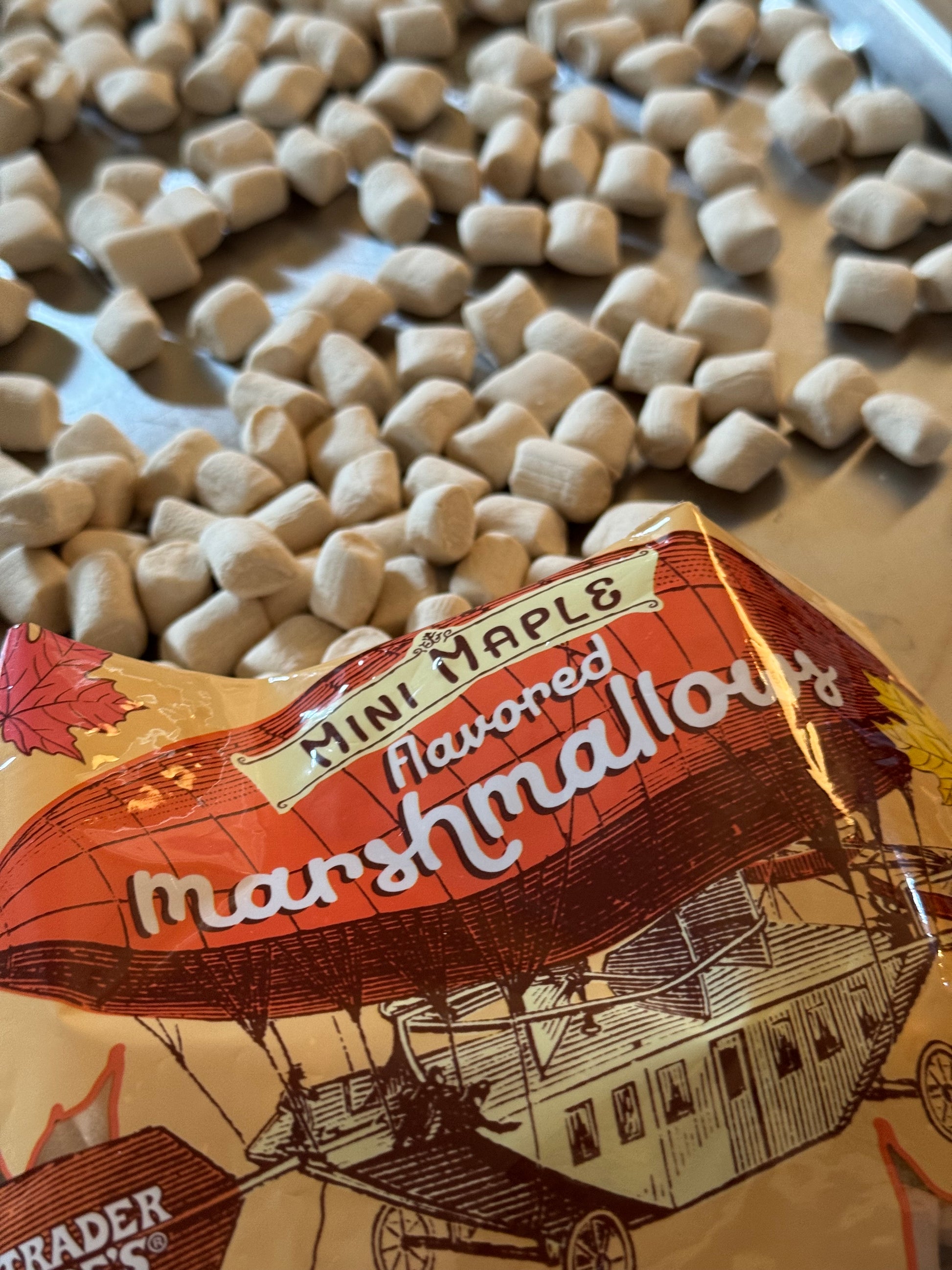 A plastic bag that says mini maple falvored marshmallows from Trader Joe's spilling mini marshmallows on to a tray