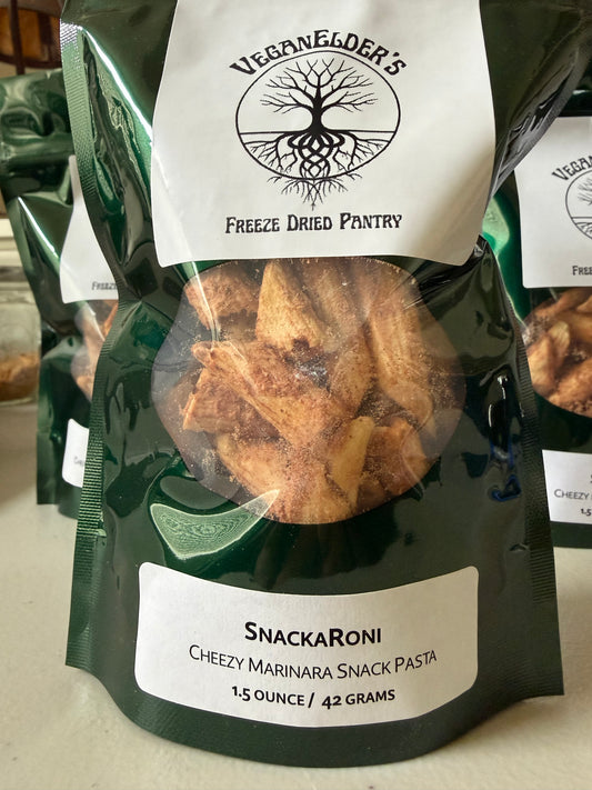 A bag of Veganelder's Freeze Dried Pantry SnackRoni Cheezy Marinara Snack Pasta, featuring a dark green and white packaging design with a clear window showing the freeze-dried pasta inside.