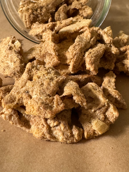 Close up of protein strips that look light and crunchy as they have tumbled out of a jar onto a table