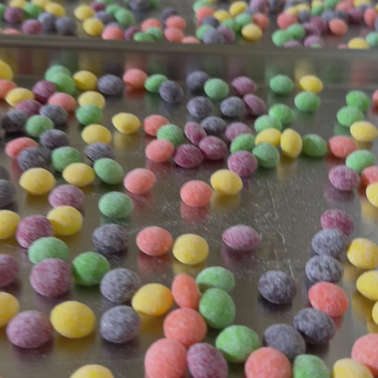Video of colorful spherical candies covered with sour candy dust siting in freeze dryer trays ready to be cooked in the freeze dryer.