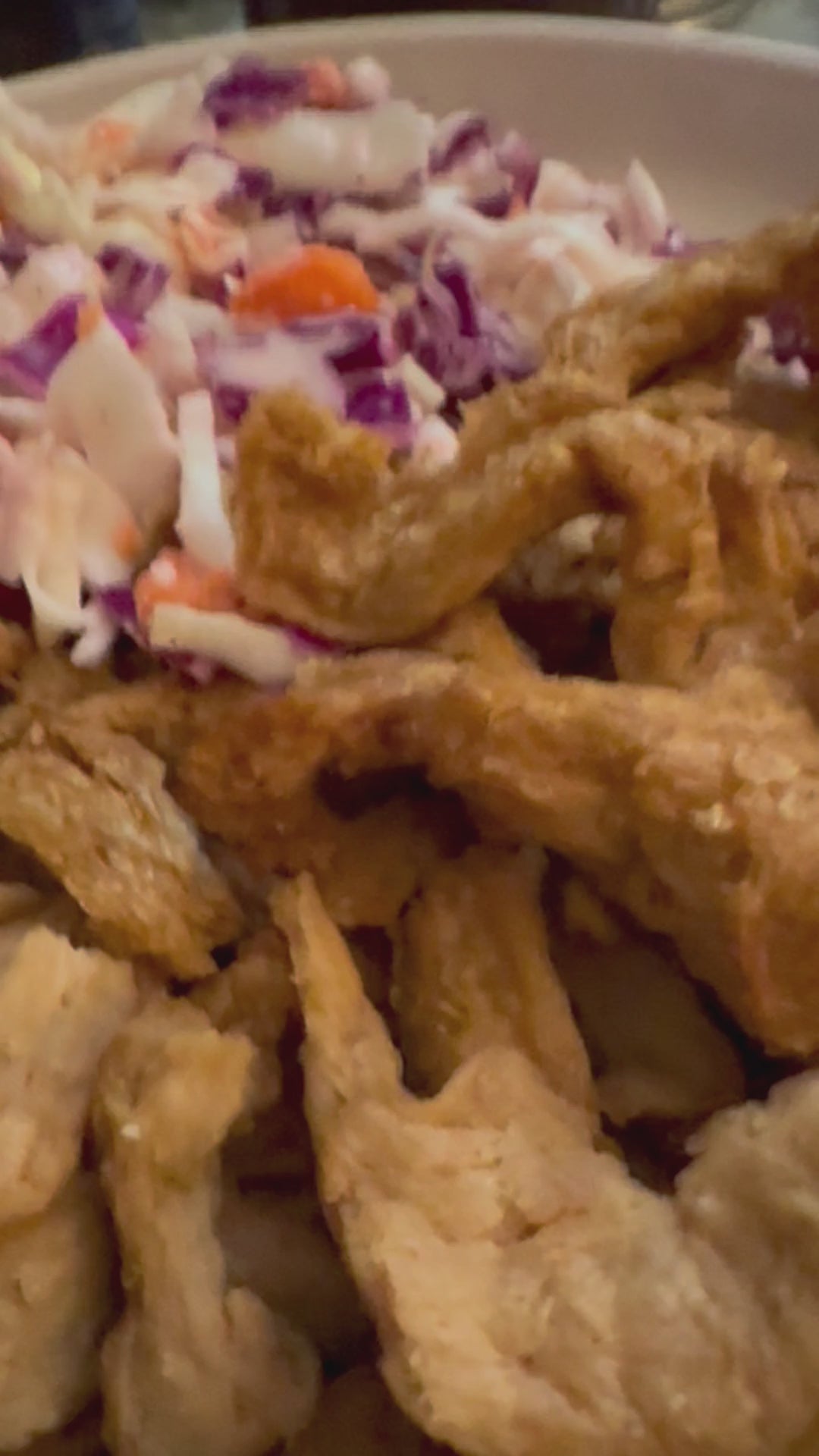 A plate of plant protein strips with tangy barbecue sauce being ladled onto the food for a delicious barbecue meal